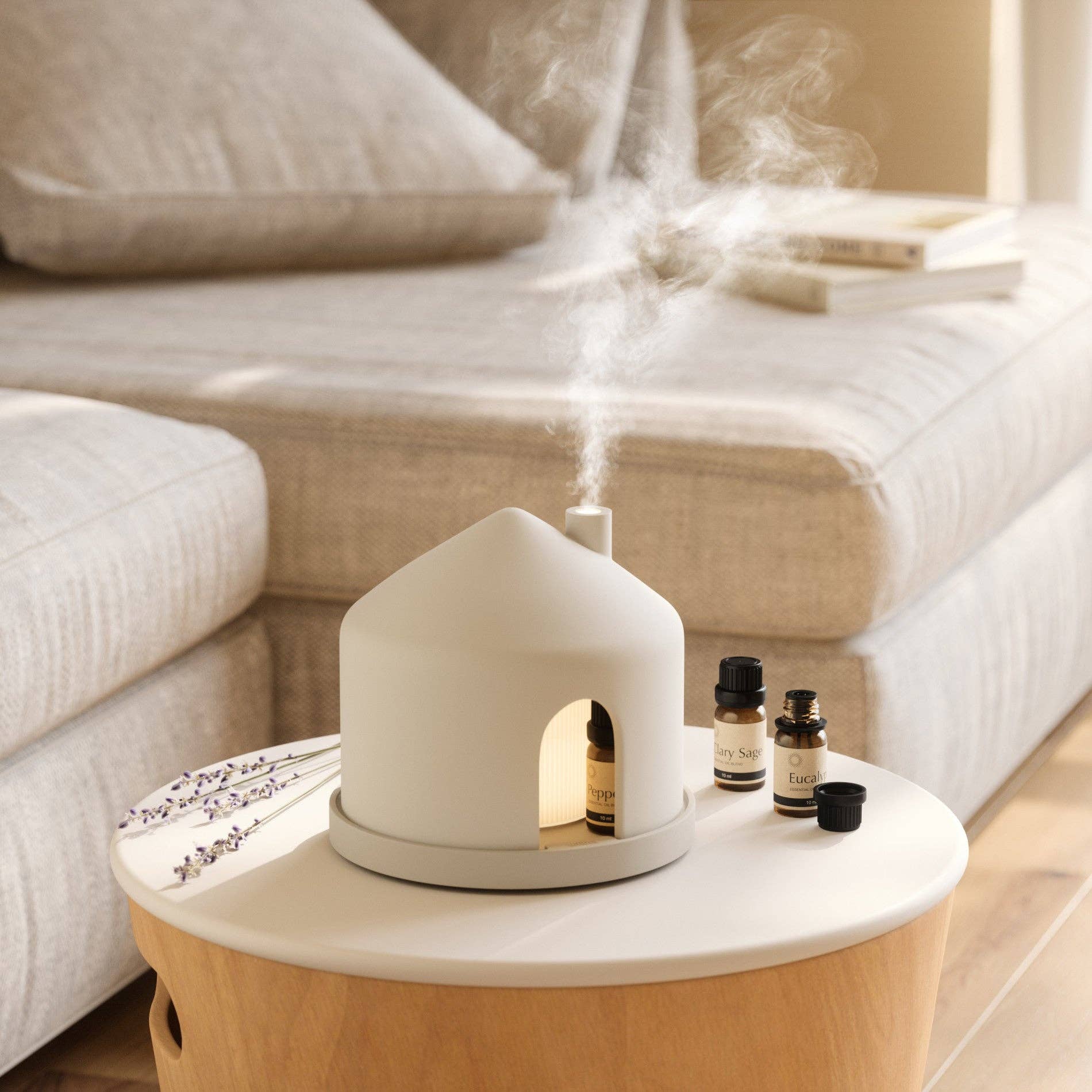 White diffuser emitting steam on a wooden table with bottles in a living room setting
