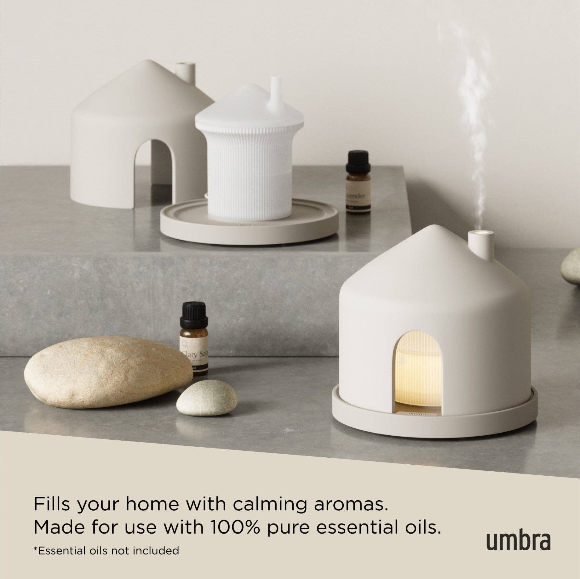 Umbra diffuser on a table with essential oils and rocks, featuring calming aromas text.
