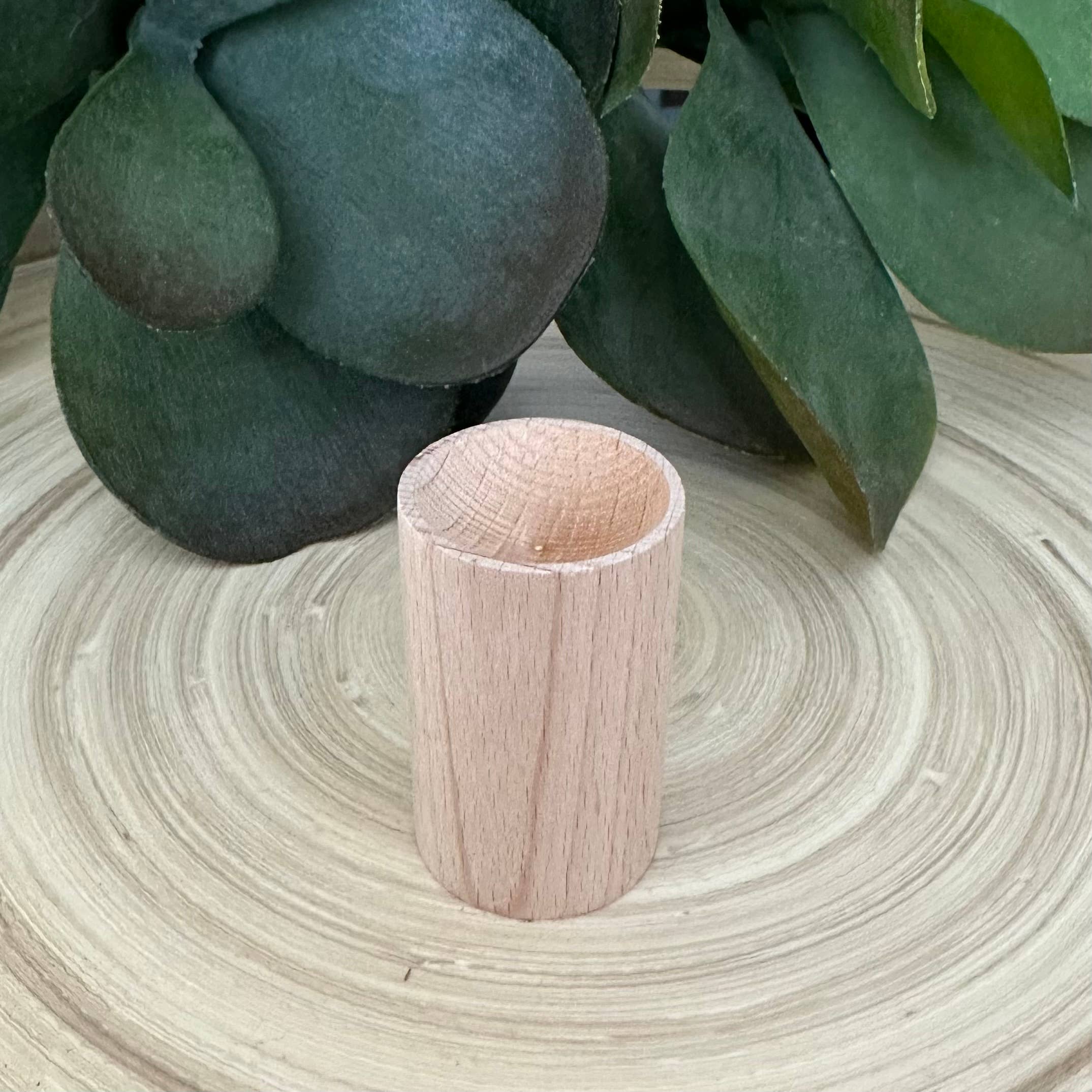 Wooden cylindrical object on a woven surface with green leaves in the background