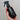 Hand holding an Aromatic Creation dark brown bottle with a spray nozzle against a neutral background