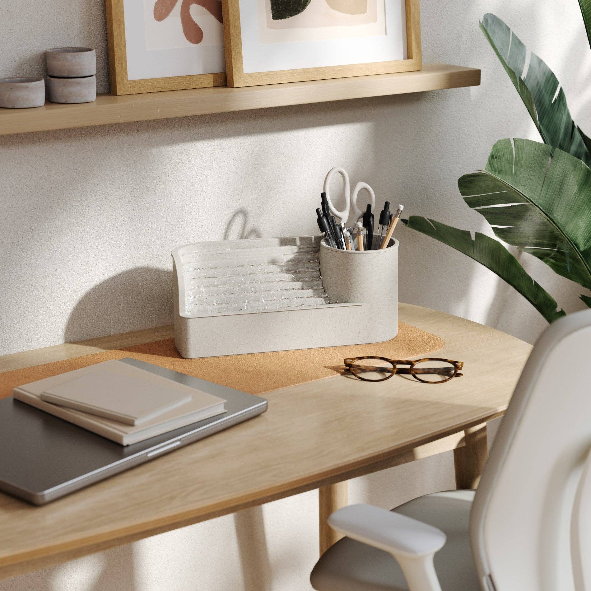 Neatly organized desk with office supplies, a plant, and framed pictures on a shelf.
